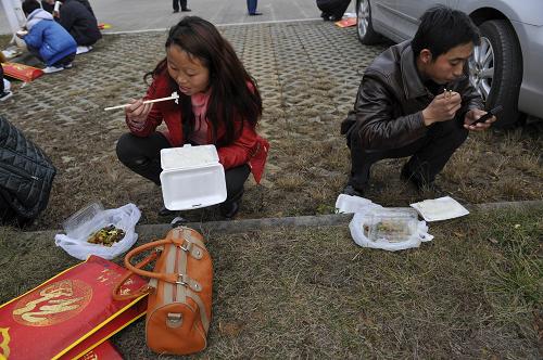 1月29日,陳順付(右)和妻子在路邊吃盒飯,準(zhǔn)備轉(zhuǎn)乘客車回家。新華社記者 歐東衢 攝