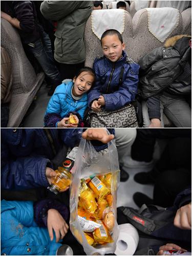 10歲的小康(左)和11歲的哥哥小周在北京讀小學(xué),這次他們跟著媽媽一起回家。由于沒有買到坐票,只好帶著小板凳坐在過道上,幸運(yùn)的是有好心人讓了個(gè)座位給他們。他們的晚飯是一袋小蛋糕,價(jià)格17元。不過兩個(gè)孩子因?yàn)榛丶姨d奮,都顧不上吃晚飯了(2月1日攝)。新華社記者 周密攝