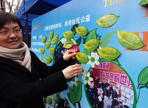 2月25日,一位女士將寫有自己個人信息、特長和愿意奉獻時間的“樹葉”卡片張貼在“捐獻時間志愿樹”上。新華社記者 任瓏 攝