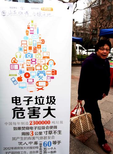 2月25日,一位市民從公益回收電子垃圾的宣傳板前走過。新華社記者 任瓏 攝