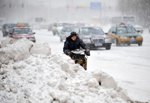 3月9日,在哈爾濱街頭,車輛和行人在風(fēng)雪中前行。新華社記者王建威攝