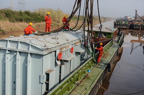 3月19日,397噸的變壓器抵達浙江湖州韋山碼頭,準備從貨船吊上岸。當日,由浙江省送變電工程公司負責運輸、安裝調試的國內電網領域變電容量最大的變壓器順利抵達浙江湖州韋山碼頭。此次運輸的變壓器重達397噸,容量3000兆伏安,是國內電網領域容量最大的變壓器,該變壓器將運往位于安吉縣的100萬伏浙北變電站,并將成為建設中的皖電東送特高壓工程的重要的一環(huán)。通過100萬伏浙北變電站,皖電東送工程可向浙江每年供電300億度(千瓦時)。皖電東送特高壓工程是我國首條同塔雙回路特高壓交流輸電工程,工程西起安徽淮南,經皖南、浙北到達上海,線路全長656公里,共有1421座鐵塔。工程計劃于2013年底投運,屆時年送電量約500億千瓦時。新華社記者 徐昱 攝