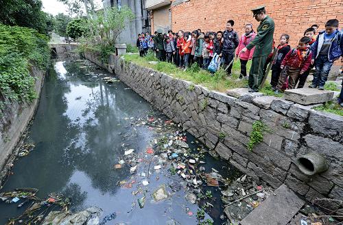 3月21日,福建省長樂市潭頭邊防民警和當(dāng)?shù)匦W(xué)生在鎮(zhèn)區(qū)周邊查看被污染的河道。新華社記者張國俊攝