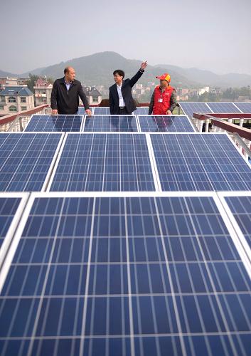 供電部門工作人員和朱建兵的家人(左一)在查看設(shè)備工作情況(3月22日攝)。不僅給自家生活供電,還能兼顧隔熱功能,并能夠并網(wǎng)供電賺錢,這是江西省蓮花縣金城大道楊家新村朱建兵家屋頂?shù)男鹿δ?。自去年國家對民間放開發(fā)電并網(wǎng)政策之后,這戶人家就投資了3萬余元,在自家樓頂上搞起了光伏發(fā)電裝置。這個月中旬正式并網(wǎng)發(fā)電后,這個普普通通的農(nóng)家四層小樓已經(jīng)在十天內(nèi)發(fā)電兩百四十多度,除去供給自家使用的十多度電,已經(jīng)向電網(wǎng)供電230度。這套發(fā)電設(shè)備裝機容量為4千瓦,按當(dāng)?shù)氐娜照諘r間,預(yù)計年發(fā)電量為5000到6000千瓦時,按照現(xiàn)行電價計算,只需要五、六年就能收回成本,而發(fā)電設(shè)備預(yù)期壽命可達25年。新華社記者周密攝