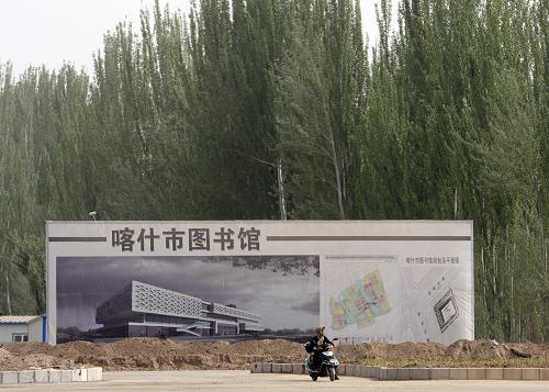一位當?shù)鼐用駨恼诮ㄔO的喀什市圖書館旁經過(4月13日攝)。新華社記者 趙戈 攝