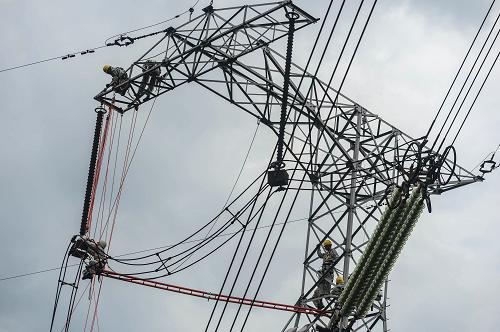 6月18日,電力員工身穿屏蔽服帶電作業(yè),更換500千伏線路跳線串絕緣子。新華社記者 韓傳號(hào) 攝