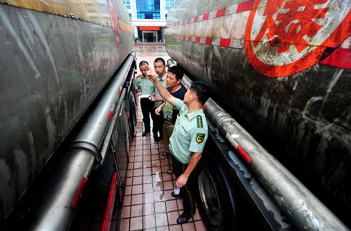 6月24日,福清邊防大隊民警在對查扣的無合法手續(xù)成品油罐車車主(左三)進(jìn)行詢問。當(dāng)日,福建省福清公安邊防大隊查獲一起涉嫌運輸無合法手續(xù)成品油案件,查扣2輛油罐車,抓獲4名涉案犯罪嫌疑人,緝獲無合法手續(xù)成品油數(shù)量近50噸,案值35萬元左右。福建省公安邊防部隊近期深入開展打擊走私專項行動,2013年以來,僅福州公安邊防支隊查獲各類無合法手續(xù)成品油案件23起,查扣無合法手續(xù)成品油907.8噸。新華社記者 魏培全 攝