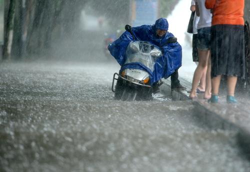 6月25日,一名騎車人在南京街頭積水嚴(yán)重的路段艱難行進(jìn)。新華社發(fā)