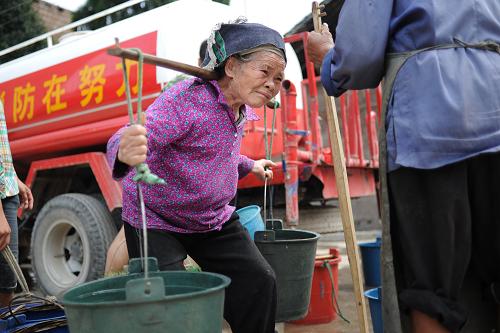 8月16日,在貴州黔南惠水縣龍井村,81歲的苗族婦女羅錦妹挑起近20斤的水桶回家。據(jù)羅錦妹說,她的兩個(gè)兒子均外出打工,現(xiàn)只有她一人獨(dú)自留守在家。入夏以來,貴州大地旱情肆虐,全省已有近半數(shù)縣城達(dá)到特旱等級。在抗旱過程中,挑水、找水、農(nóng)業(yè)生產(chǎn)等都需要大量勞動力。然而目前貴州有大量農(nóng)村壯勞力通過進(jìn)城打工等方式離開農(nóng)村,因此農(nóng)村留守人口多為婦女、兒童和老人。記者在一些受旱非常嚴(yán)重的村寨中看到,抗旱的主力軍竟然大部分是留守老弱婦孺,上至八十歲的老人,下至十來歲的孩童都肩挑水桶,邁著搖晃的步伐挑水回家。在抗旱之余,他們還需要承擔(dān)洗衣做飯、喂養(yǎng)牲口、下地勞作等沉重勞動。青壯年男性勞動力不足已然成為當(dāng)前抗旱工作中一項(xiàng)棘手的問題。新華社記者 劉續(xù) 攝