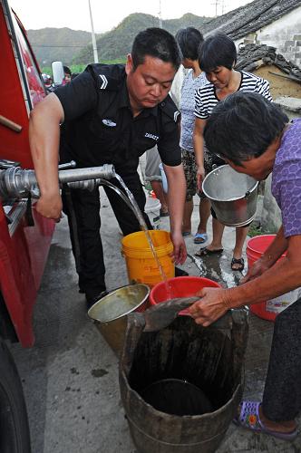 浙江省新昌縣小將鎮(zhèn)派出所消防隊(duì)隊(duì)長吳鑫鑫在用消防車出水管為嚴(yán)重缺水的該鎮(zhèn)結(jié)局山村村民送上飲用水(8月13日攝)。新華社記者 譚進(jìn) 攝