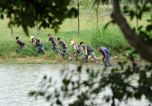8月20日,幾名實訓隊員和農民(右一)一起在魚塘邊拉網捕魚。新華社記者 孫參 攝