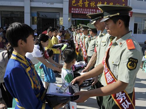 8月24日,武警阿拉善右旗邊防機(jī)動(dòng)中隊(duì)的邊防干警在為巴丹吉林鎮(zhèn)泰隆社區(qū)的留守兒童贈(zèng)送學(xué)習(xí)用品。新華社記者 李欣 攝