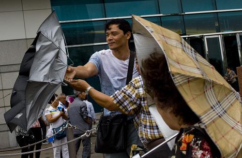 9月22日,香港灣仔街頭一位游客的傘被風(fēng)吹翻。新華社記者 呂小煒 攝