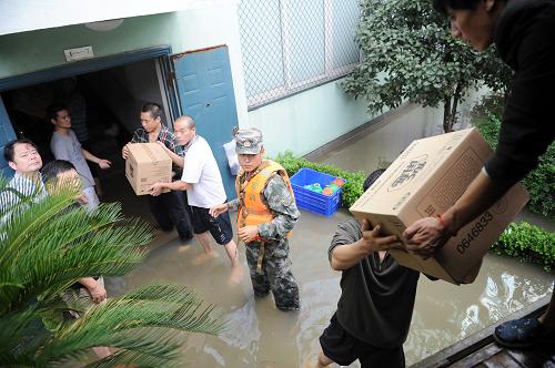 10月10日,浙江余姚鳳山街道工作人員與南京軍區(qū)救災(zāi)官兵一起,涉水將150多箱餅干和41箱水緊急運(yùn)送到被積水圍困的劍江村大葉園林公司600多位外來務(wù)工人員手中。新華社記者 鞠煥宗 攝