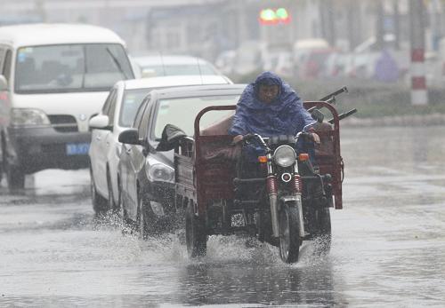 11月24日,一名三輪車(chē)司機(jī)在煙臺(tái)市勝利路冒雨行進(jìn)。新華社發(fā)(申吉忠 攝)