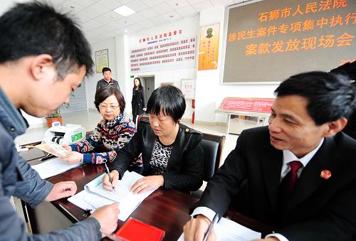 1月8日,在石獅市人民法院涉民生案件專項集中執(zhí)行案款現(xiàn)場發(fā)放活動中,工作人員在為農(nóng)民工辦理被拖欠工資領(lǐng)取手續(xù)。當(dāng)日,福建省石獅市人民法院舉行了涉民生案件專項集中執(zhí)行案款現(xiàn)場發(fā)放活動,為在3個系列案件中涉及的32名農(nóng)民工發(fā)放被拖欠的工資款共98萬元。新華社記者 林善傳 攝
