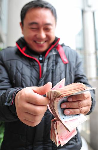 1月8日,河南省周口市鹿邑縣王皮溜鎮(zhèn)小谷莊行政村村民許玉欽在數(shù)著剛領(lǐng)到的被拖欠的工資。新華社記者 林善傳 攝