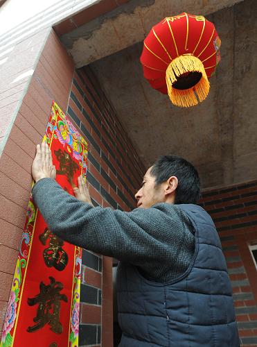 1月30日,在蘆山縣蘆陽鎮(zhèn)黎明新村聚居點(diǎn),村民任學(xué)康為自家新居貼春聯(lián)。新華社記者 薛玉斌 攝