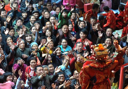 2月1日,李永順在長(zhǎng)沙火宮殿古戲臺(tái)上為觀(guān)眾表演《財(cái)神送福》。春節(jié)逛火宮殿廟會(huì)是長(zhǎng)沙市民的“必修課”,而“財(cái)神爺送福”是每屆火宮殿廟會(huì)的重頭戲,也是觀(guān)眾參與度最高的節(jié)目。大年初二,記者來(lái)到長(zhǎng)沙火宮殿,用鏡頭記錄下這位火宮殿“財(cái)神爺”的廟會(huì)春節(jié)。今年35歲的李永順是湖南省京劇保護(hù)傳承中心的一名國(guó)家二級(jí)演員,在長(zhǎng)沙火宮殿廟會(huì)表演“財(cái)神爺送福”已經(jīng)11個(gè)年頭。據(jù)悉,火宮殿迎春廟會(huì)已經(jīng)舉辦了20多屆,但2014年的人氣最旺,每天都有近萬(wàn)名市民來(lái)火宮殿看廟會(huì)。上午11點(diǎn)多,長(zhǎng)沙坡子街火宮殿人山人海。隨著一陣歡快的開(kāi)場(chǎng)鑼鼓聲,現(xiàn)場(chǎng)市民開(kāi)始?xì)g呼:“‘財(cái)神爺’要派發(fā)金元寶了,快點(diǎn)搶??!”只見(jiàn)“財(cái)神爺”在戲臺(tái)上一邊走著臺(tái)步賣(mài)力表演一邊變戲法般將一個(gè)個(gè)“金元寶”和“紅包”撒向跳躍的人群。臨近中午時(shí)分,記者在演員臨時(shí)休息室見(jiàn)到李永順,他還沒(méi)卸妝,臉上涂著濃厚的脂粉、身穿厚重戲服,“現(xiàn)在可還不能卸妝,下午還得演一場(chǎng)呢!”李永順告訴記者,每天中午、晚上兩場(chǎng)演出,每場(chǎng)持續(xù)15分鐘。每次演出前都要提前一個(gè)小時(shí)化妝更衣,有的時(shí)候遇見(jiàn)觀(guān)眾熱情高漲還要加演。一天下來(lái)經(jīng)常汗流浹背、腰酸背痛。“每年的除夕到正月十五期間,我基
