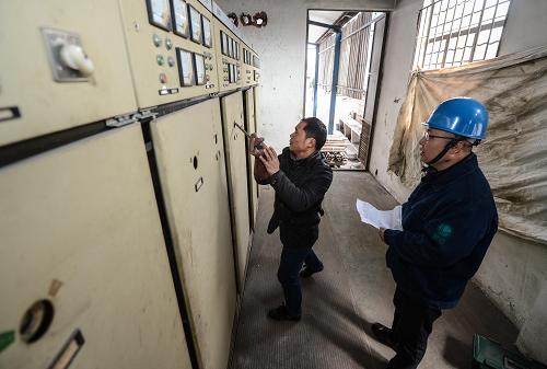 2月10日,在蕭山區(qū)供電公司工作人員監(jiān)護下,杭州一家紡織企業(yè)的電工在進行變壓器復電操作。新華社記者 徐昱 攝