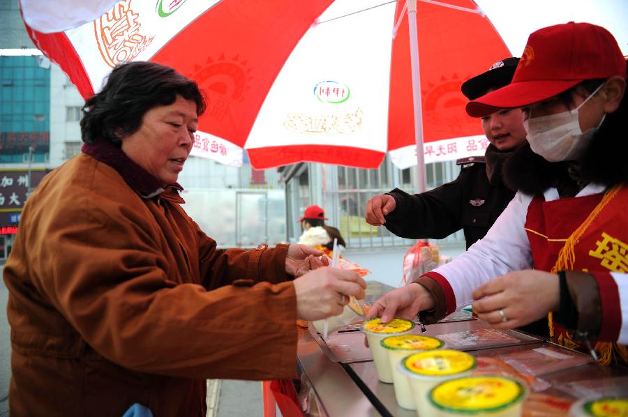 1月26日,一位旅客(左)在領(lǐng)取免費(fèi)早餐。當(dāng)日是2013年春運(yùn)的第一天,合肥市瑤海區(qū)城管局請(qǐng)來春運(yùn)志愿者在火車站廣場(chǎng)設(shè)立“春運(yùn)志愿便民服務(wù)站”,為在火車站乘車的旅客提供免費(fèi)早餐。過往的旅客憑手中的火車票即可免費(fèi)領(lǐng)到一個(gè)面包、一個(gè)熱包子和一杯熱豆?jié){。據(jù)了解,免費(fèi)向旅客發(fā)放早餐的活動(dòng)將一直持續(xù)到整個(gè)春運(yùn)結(jié)束。 新華社記者 杜宇攝