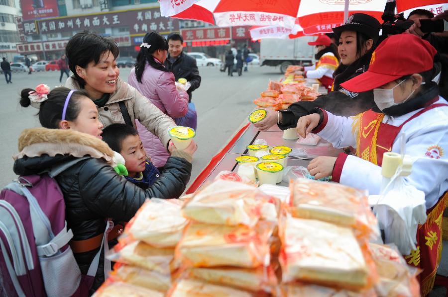 1月26日,春運(yùn)志愿者為即將乘坐列車的旅客送上早餐。新華社記者 杜宇攝
