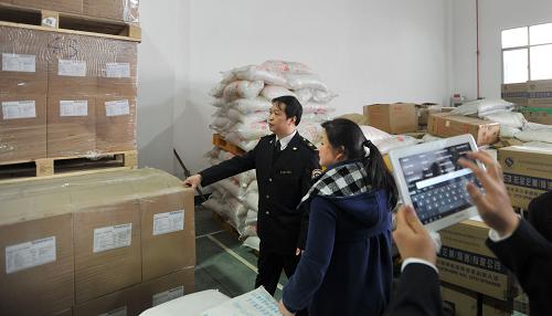 3月14日,湖南省質監(jiān)部門的一名執(zhí)法人員(左一)在長沙一家食品企業(yè)的原料庫房里檢查,他的同事(右一)正使用裝有“食安通”巡查終端的電子設備對檢查過程進行記錄。 新華社記者 李尕攝