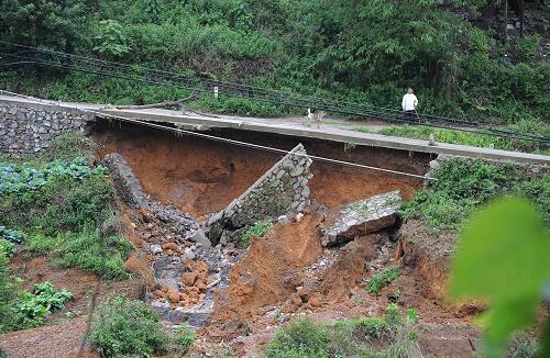 5月8日,在貴州省丹寨縣龍泉鎮(zhèn)馬寨村,一名村民從一處因暴雨損壞的公路旁走過。新華社發(fā)(陳沛亮 攝)