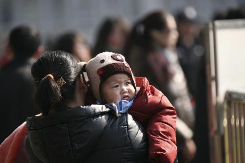 1月15日,在南京火車(chē)站,一位女士抱著小孩準(zhǔn)備進(jìn)站乘車(chē)。新華社發(fā)(王巖棣 攝)