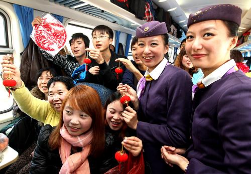 1月16日,毛靜、毛雯姐妹倆在列車上為旅客送上春聯(lián)及安全出行手冊(cè)后與旅客互動(dòng)聯(lián)誼。新華社記者 陳飛 攝