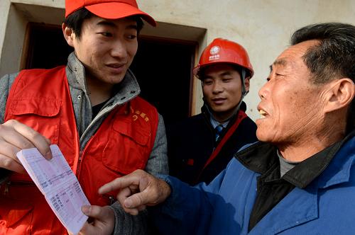1月16日,肥西縣供電公司的青年志愿者張珺(左)給銘傳鄉(xiāng)鴿子籠村五保戶劉甫忠(右)講解每月返還用電費用政策。新華社記者 郭晨 攝
