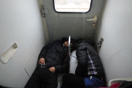 1月16日,在昆明開(kāi)往上海的K80次列車(chē)上,兩名旅客睡在車(chē)廂連接處。新華社記者 劉續(xù) 攝
