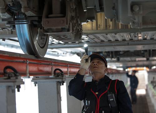 1月16日,重慶車輛段的一名動(dòng)車機(jī)械師手持錄像電筒對(duì)動(dòng)車組底部的各種設(shè)備進(jìn)行逐一拍攝和檢查。新華社記者 劉潺 攝