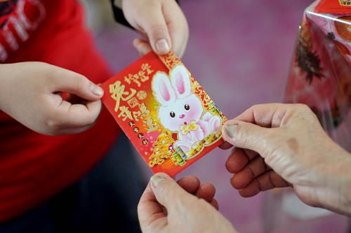 2月3日,在馬來西亞柔佛州巴羅小鎮(zhèn),一名長輩給小輩新年壓歲錢。新華社發(fā)(張紋綜攝)