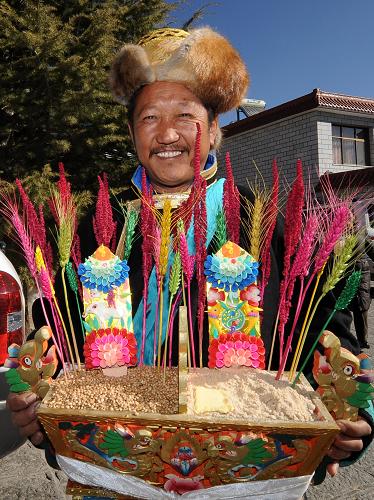 3月5日,端著吉祥“切瑪”的藏族同胞到鄰居家拜年。新華社記者 覺(jué)果 攝