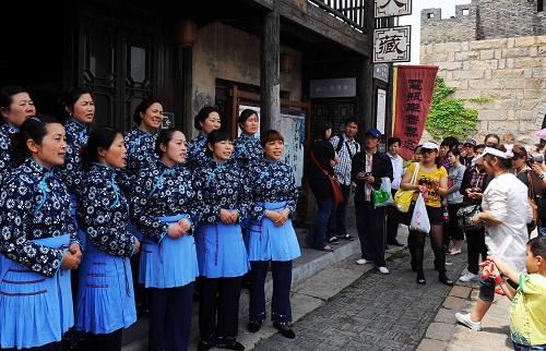 5月1日,沙家浜蘆蕩深處的老街上,身著傳統(tǒng)水鄉(xiāng)服飾的婦女在為游客表演白茆山歌。當日,萬余名游客趁著五一小長假來到常熟沙家浜景區(qū),泛舟蘆蕩深處,享受自然風光。新華社記者 陳琪 攝