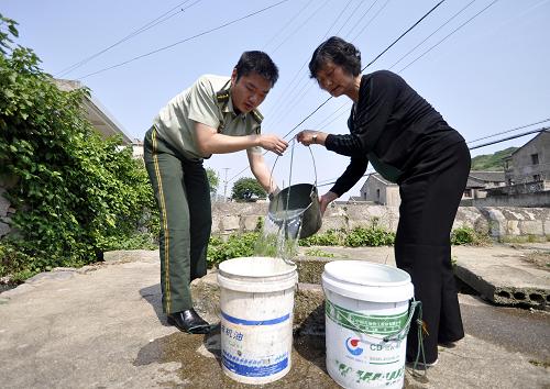 5月31日,舟山市普陀區(qū)蝦峙鎮(zhèn)邊防派出所民警蔣繼振(左)幫助居民取用井水。目前島上居民取水都由邊防派出所民警統(tǒng)一安排。新華社記者 徐昱 攝