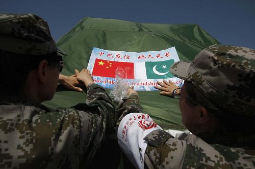 10月22日,在巴基斯坦信德省昆瑞地區(qū),中國人民解放軍醫(yī)療救援隊隊員將中巴友誼標(biāo)語貼在帳篷醫(yī)院外。新華社記者 李翔 攝