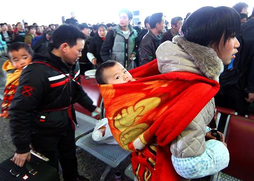 1月8日,來自四川成都地區(qū)的黃福安夫婦帶著幼小的孩子在上?;疖囌竞蜍?。新華社記者 陳飛攝