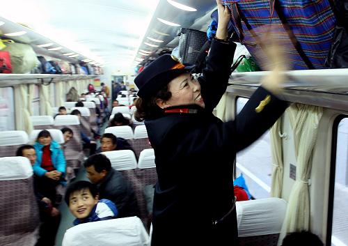1月8日,列車乘務(wù)員魏寧霞在上海開往西寧的K376次列車上為乘客整理行李。新華社記者 陳飛攝