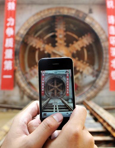 5月28日,一名工程人員在用手機(jī)拍攝盾構(gòu)隧道掘進(jìn)機(jī)。當(dāng)日,由中國中鐵股份有限公司總承包的鄭州市地鐵2號(hào)線一期工程首段盾構(gòu)區(qū)間(向陽路站——南環(huán)路站右線)順利貫通。南環(huán)路站至向陽路站區(qū)間隧道直徑6.28米,右線區(qū)間設(shè)計(jì)土方外運(yùn)40486立方米、管片拼裝870環(huán)(每環(huán)1.5米),全長1306米。鄭州市地鐵2號(hào)線一期工程首段盾構(gòu)區(qū)間(向陽路站——南環(huán)路站右線)工程歷時(shí)5個(gè)月,比預(yù)計(jì)工期提前了64天。鄭州地鐵2號(hào)線一期工程起于廣播臺(tái)站,止于南四環(huán)站,全長20.4公里,共設(shè)車站16座,工程預(yù)計(jì)2013年底全線貫通。新華社記者 李博 攝
