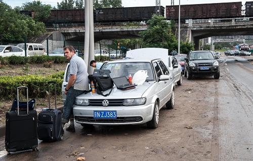 7月22日,一位被困在京港澳高速出京方向大瓦窯橋路段的外國人晾曬自己的行李和電腦。新華社記者 張宇 攝