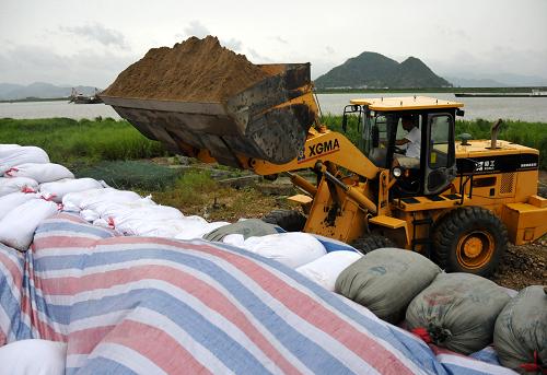 8月7日,在浙江臺(tái)州市三門縣,推土車搬運(yùn)沙石加固海塘壩,防止海水倒灌。新華社發(fā)(郟策 攝)