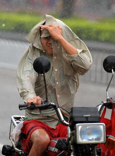 8月17日,一名海口市民在風(fēng)雨中騎行。新華社記者 郭程 攝