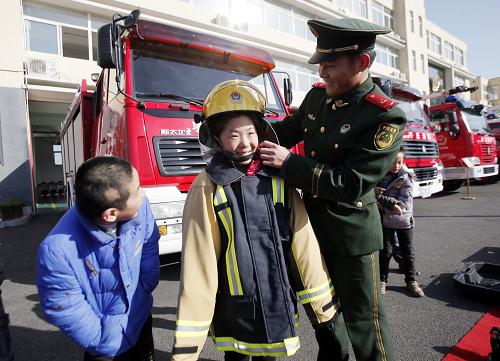 11月11日,山東省滕州市消防大隊(duì)?wèi)?zhàn)士陳慶雷(右)幫助留守兒童穿消防服。當(dāng)日,山東省滕州市消防大隊(duì)迎來一群“小戰(zhàn)士”,他們是滕州市義工第一留守兒童學(xué)校的10名留守兒童。孩子們應(yīng)邀利用周末時(shí)間來到消防大隊(duì)向消防戰(zhàn)士們學(xué)習(xí)消防知識,體驗(yàn)消防器械。
