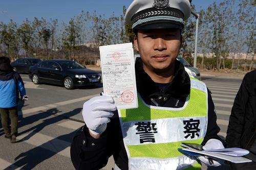 1月1日,南昌市公安交通管理局紅谷灘大隊的交警在展示給闖紅燈的車輛開具的罰單。新華社記者 宋振平 攝