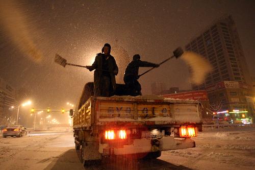 1月2日,道路養(yǎng)護(hù)工人在山東省煙臺(tái)市南大街拋撒融雪劑。新華社發(fā)(申吉忠 攝)