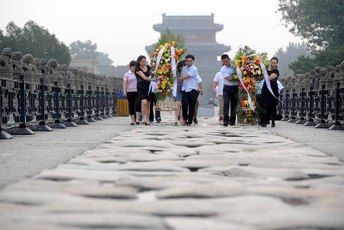 7月7日,參加活動(dòng)的青年黨員和團(tuán)員在盧溝橋上擺放花籃。新華社記者 公磊 攝
