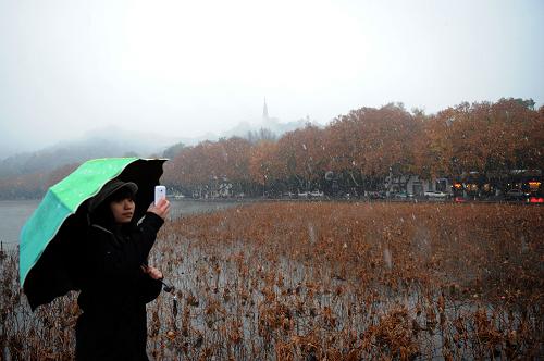 12月16日,一位游客冒雪在杭州西湖欣賞雪景。新華社記者 鞠煥宗 攝