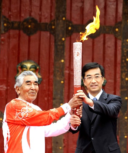 奧運圣火在拉薩傳遞 6月21日,在世界物質文化遺產(chǎn)拉薩羅布林卡公園廣場前,第一棒火炬手、西藏著名登山家貢布(左)從西藏自治區(qū)副主席兼拉薩市委書記秦宜智手中接過火炬。當日,北京奧運會圣火傳遞活動在西藏拉薩舉行。 新華社記者普布扎西攝